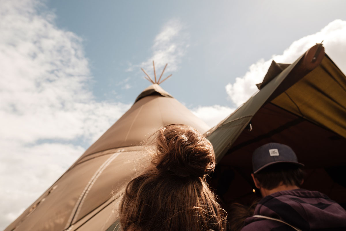 Zwei Besuchende des Skandaløs Festivals gehen an Zelten vorbei