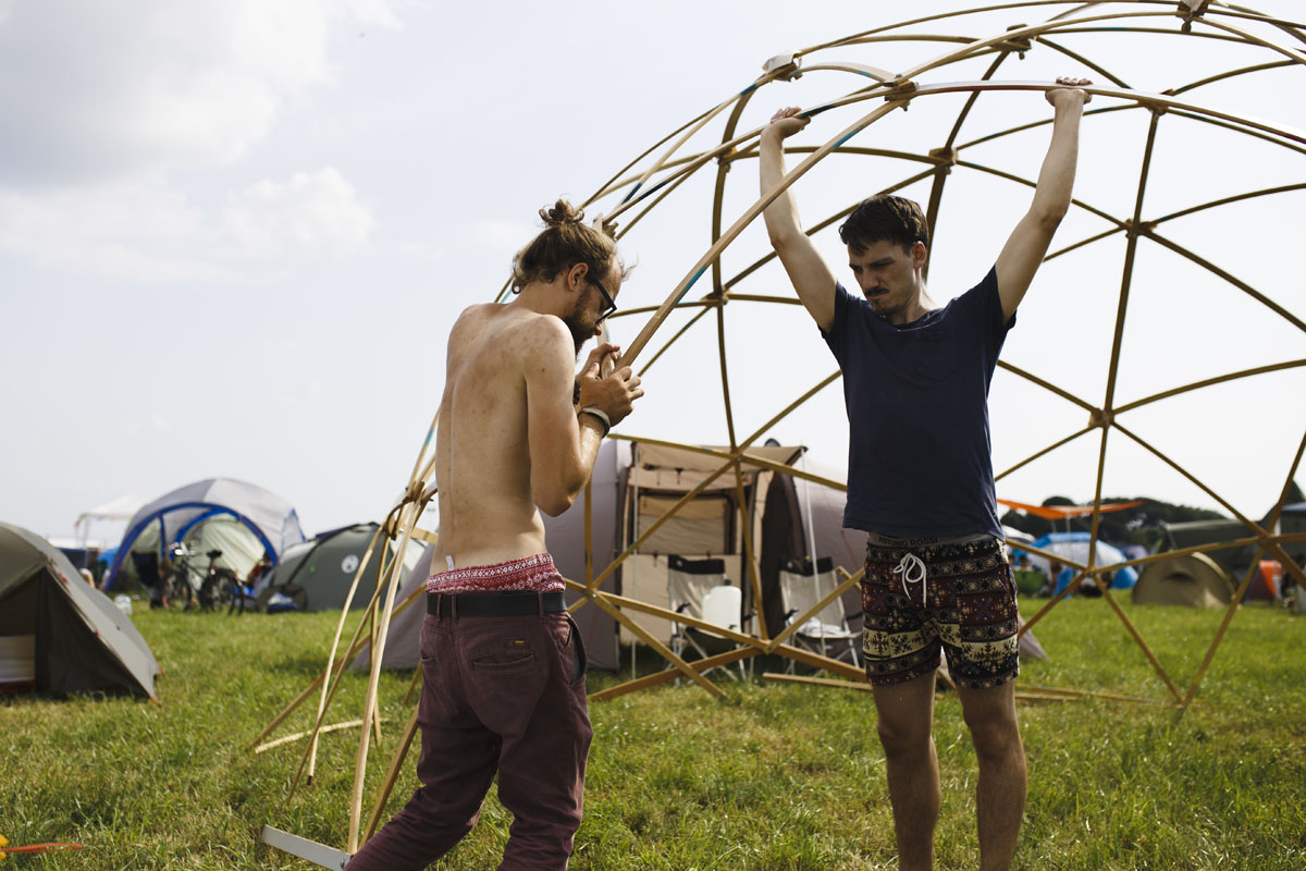 Zwei Männer bauen ein Zelt aus Holzelementen auf